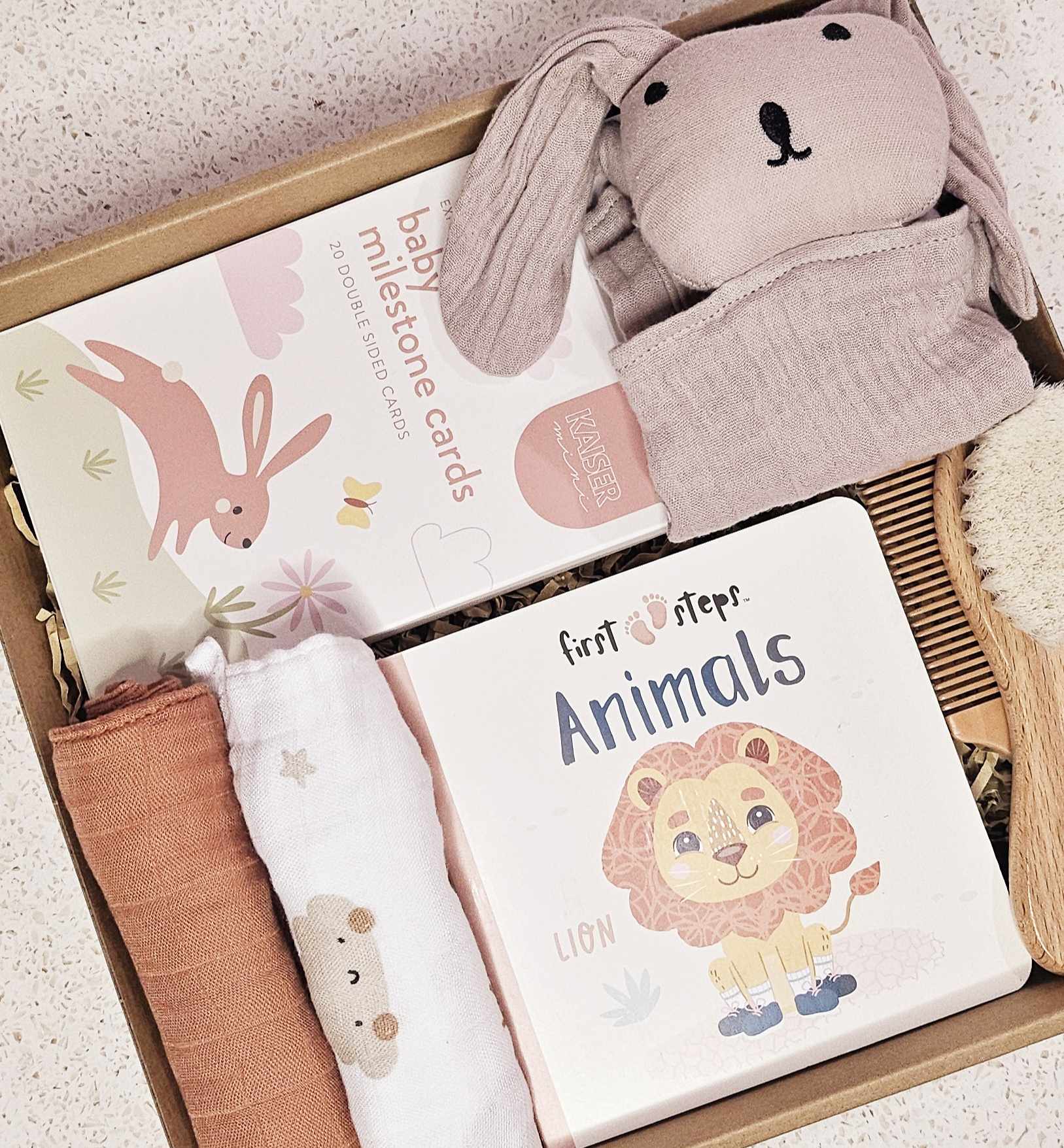 Image of The Little Snuggle Baby Gift Box: The Little Snuggle Baby Gift Box filled with milestone cards, soft baby book, small comforters, comb, brush, and a rabbit comforter, elegantly presented with a satin bow.