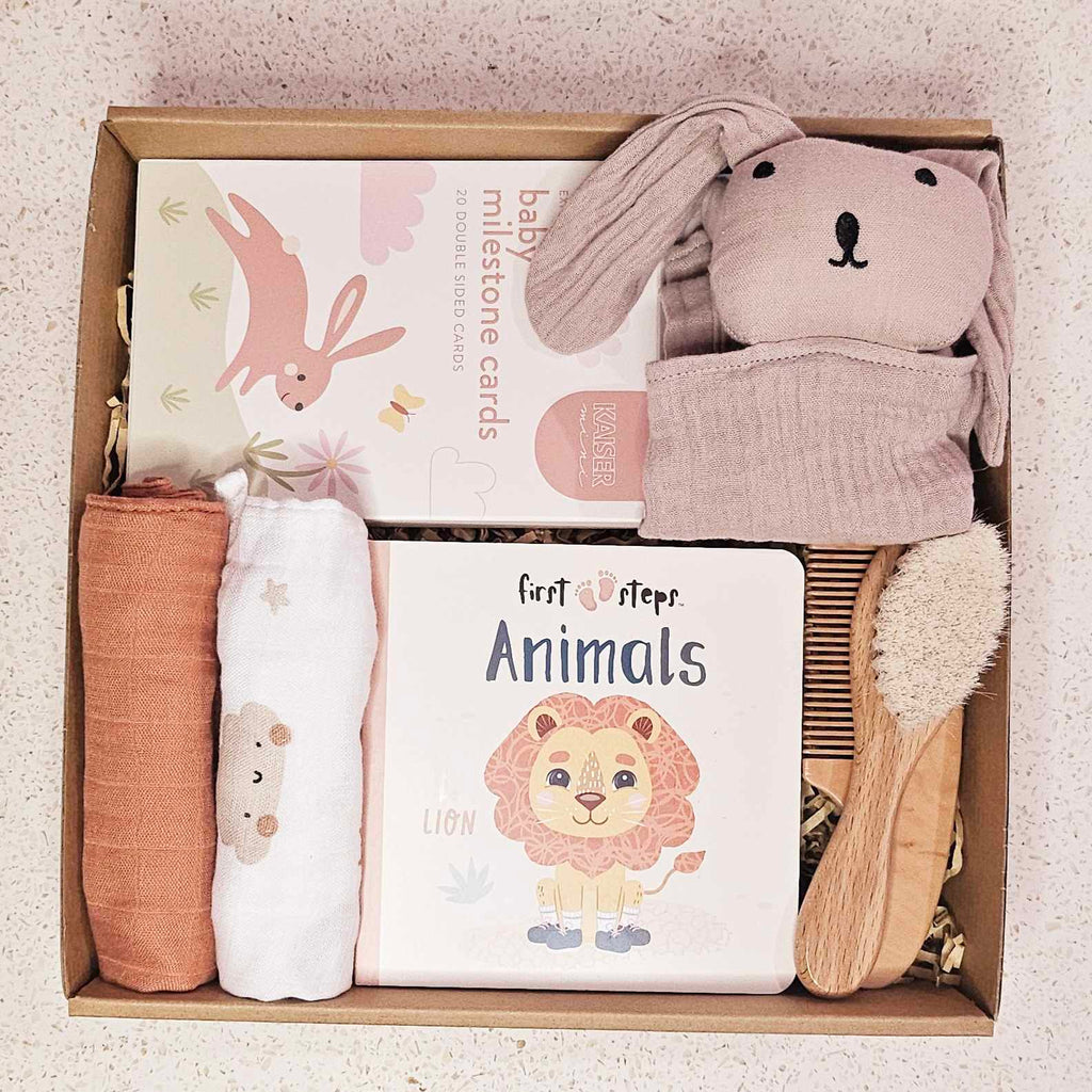 Image of The Little Snuggle Baby Gift Box: The Little Snuggle Baby Gift Box filled with milestone cards, soft baby book, small comforters, comb, brush, and a rabbit comforter, elegantly presented with a satin bow.