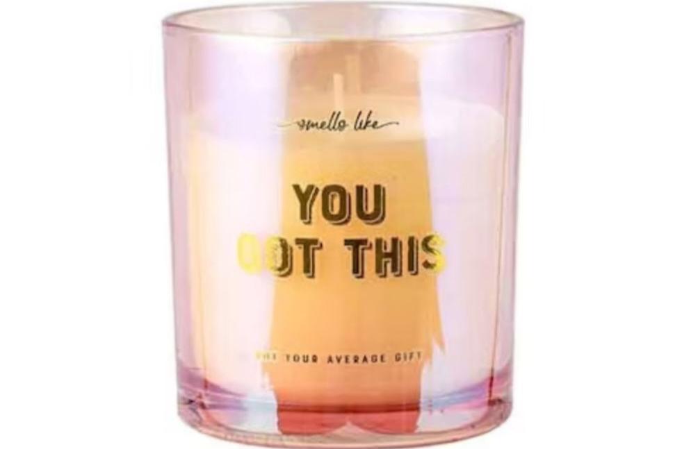 A motivational candle labeled 'You Got This' with a warm, glowing flame, placed on a rustic wooden surface. The candle features a simple, elegant design, conveying a sense of encouragement and positivity.