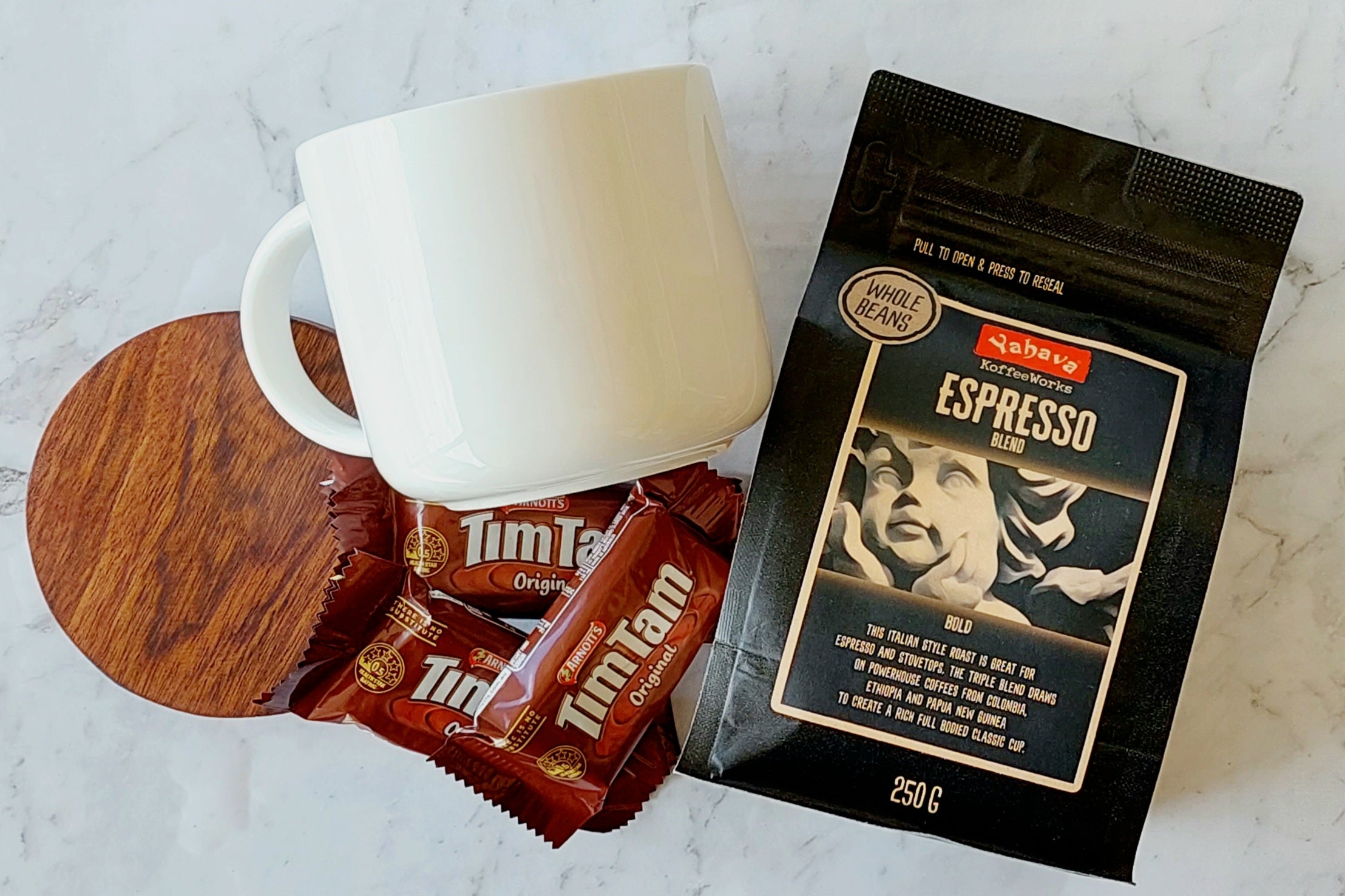 Bold Coffee Lover's Gift: A perfect package for coffee enthusiasts. Includes a 440ml Maxwell Williams white mug, 250g Yahava Koffee Works Espresso Whole Beans, three single-serve Tim Tams, and a wooden drink coaster. Ideal for espresso and stovetop brewing.