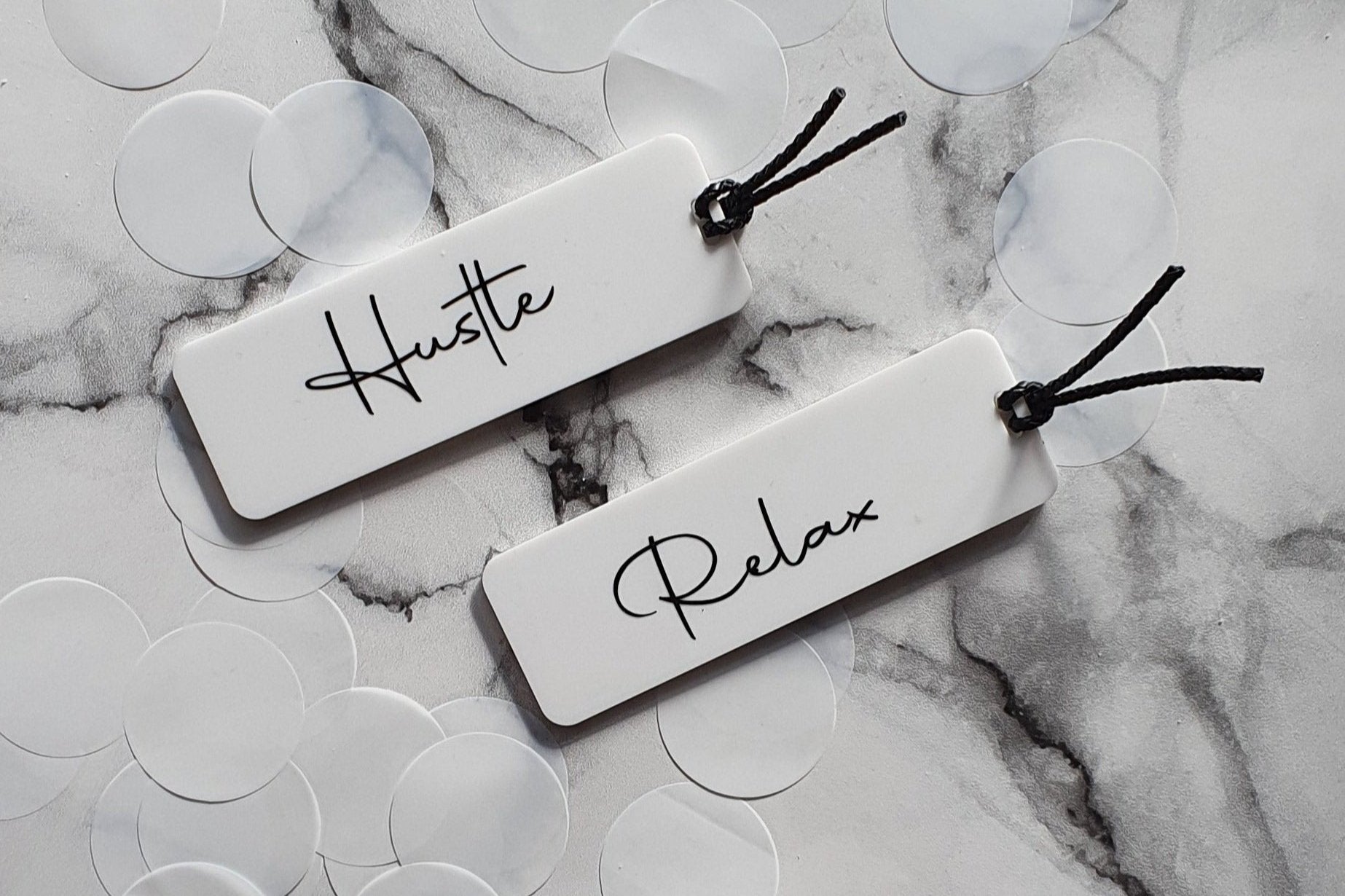 Set of vibrant acrylic bookmarks featuring motivational designs that say 'Hustle' and 'Relax.' Each bookmark is beautifully crafted, showcasing a sleek finish and eye-catching colors, perfect for inspiring productivity and encouraging downtime while reading.