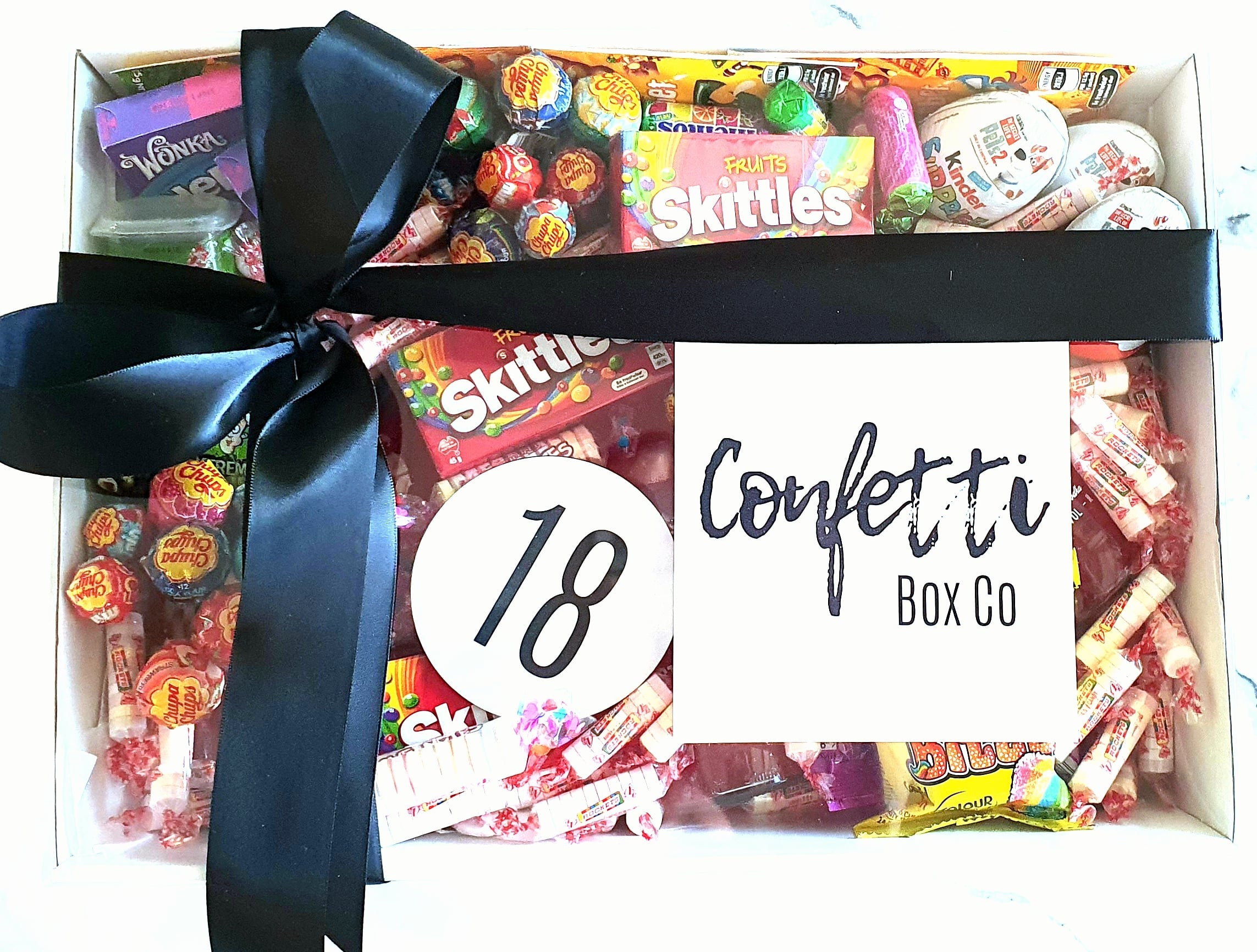 Birthday Celebration Gift Box: The ultimate treat for sweet lovers! Packed with 3 Vodka Cruisers, a reusable drinks coaster (customizable by age), Wonka Nerds, Warheads, Wizz Fizz Cones, Skittles, Kinder Eggs, Chupa Chup Bites, 30 Chupa Chups, and a variety of candies including Mini Rockets and Mentos. Perfect for indulging on their special day.