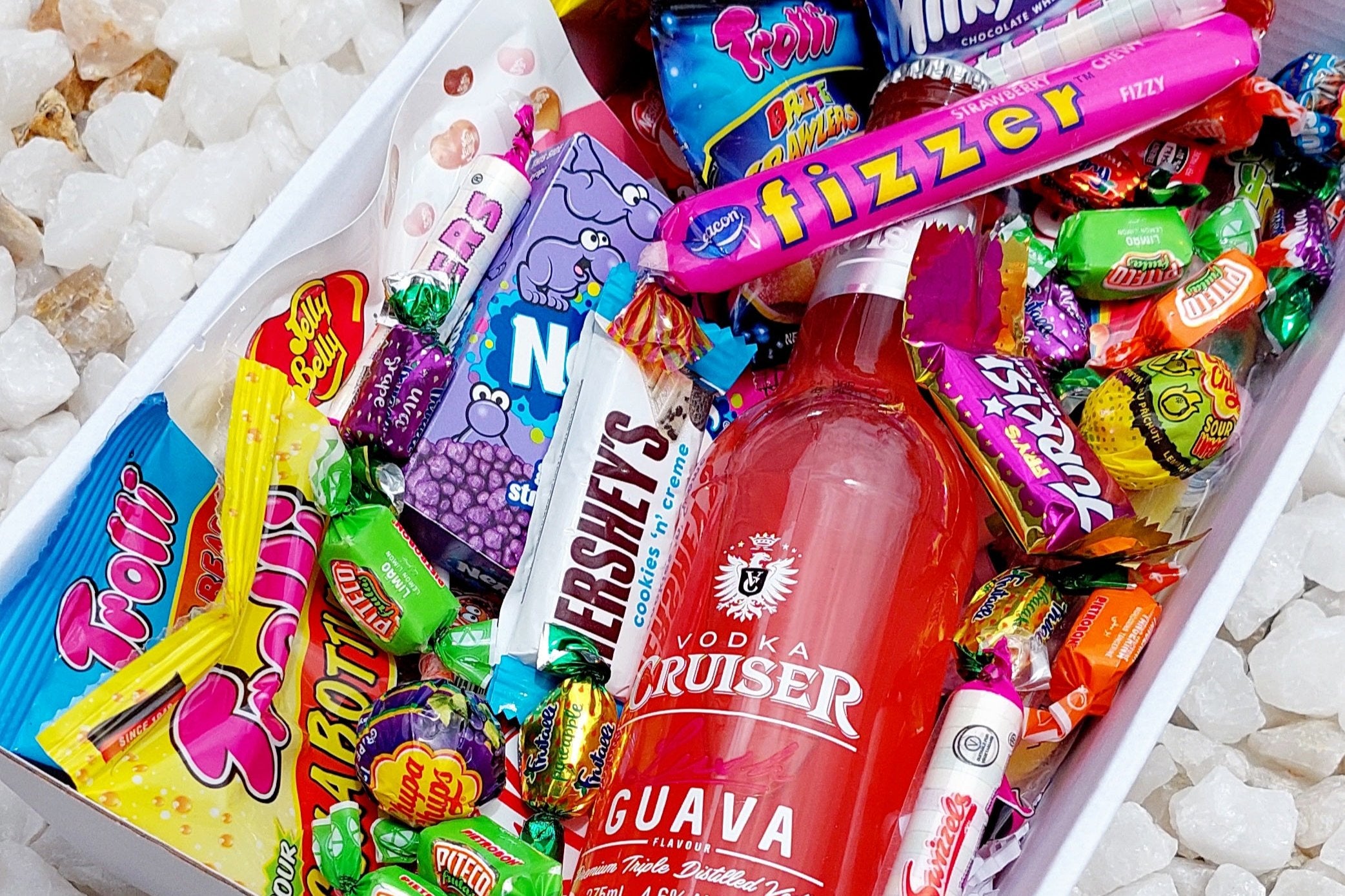 Experience the ultimate sweet escape with this enticing Vodka Cruiser treat box! Inside, you'll uncover a tantalizing array of goodies including 5 mixed Trolli bags, Chupa Chups Sour Bites, Jelly Belly pack, Fizzer, Mini Kit Kats, assorted mini chocolates, Nerds box, Skittles box, plus an abundance of additional Fizzers and lollies to top it off. Perfect for adding a touch of sweetness to any celebration or as a delightful gift for the candy connoisseur in your life!