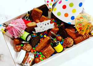 Ultimate Birthday Bash Box: Celebrate in style with a fun-filled box packed with treats and party essentials! Includes Tim Tams, Mini M&Ms, Mars or Snickers, Mini Nutella, Oreos, Ferrero Rocher, party blowers, hats, poppers, candles, and more. Topped with confetti and a free personalized message for the perfect birthday celebration.